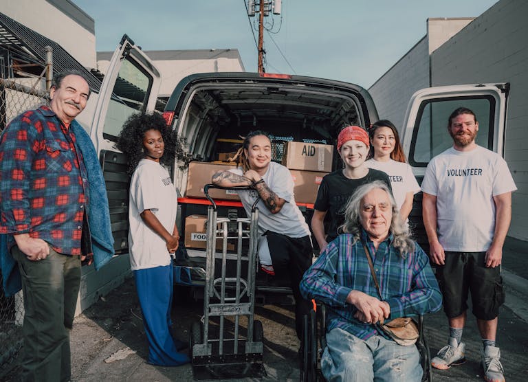 A diverse group of volunteers packing aid supplies into a van for donation.